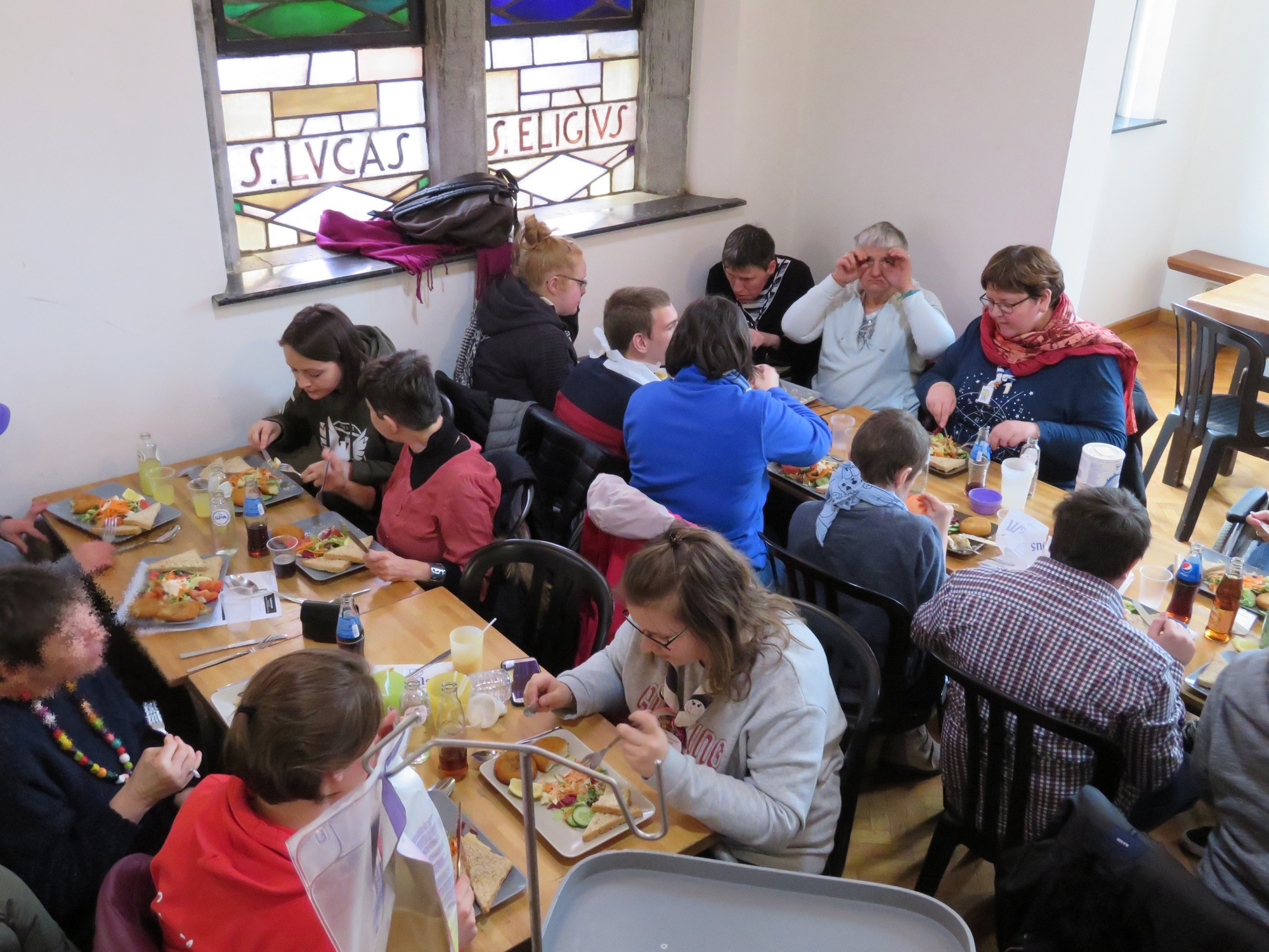 Dîner à Maredsous (2019). Personnes en situation de handicap et jeunes bénévoles sont assis à table.