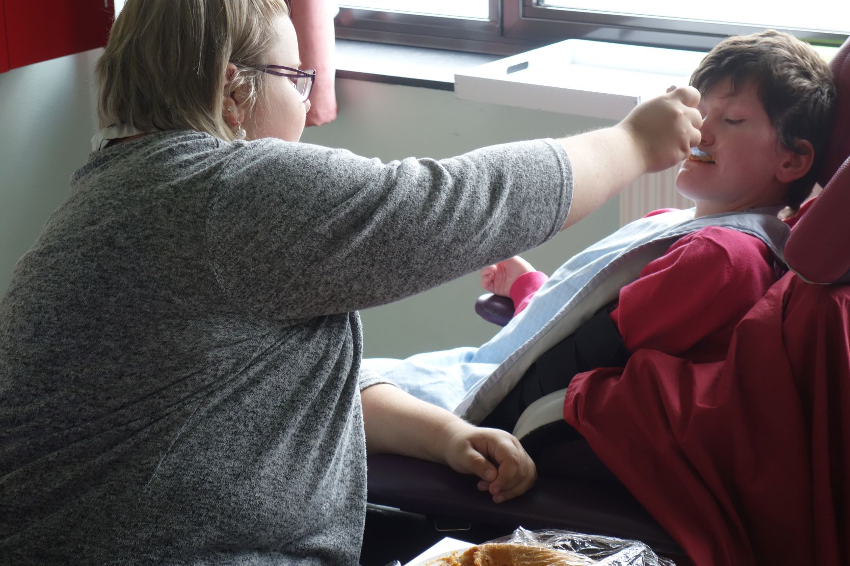 Jeune fille aidant une personne en situation de handicap à manger.